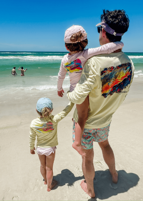 Family at the beach wearing matching Mr. Turtlehead Performance Fishing Shirts with sea turtle graphics, highlighting kids' UPF 50+ sun protection.