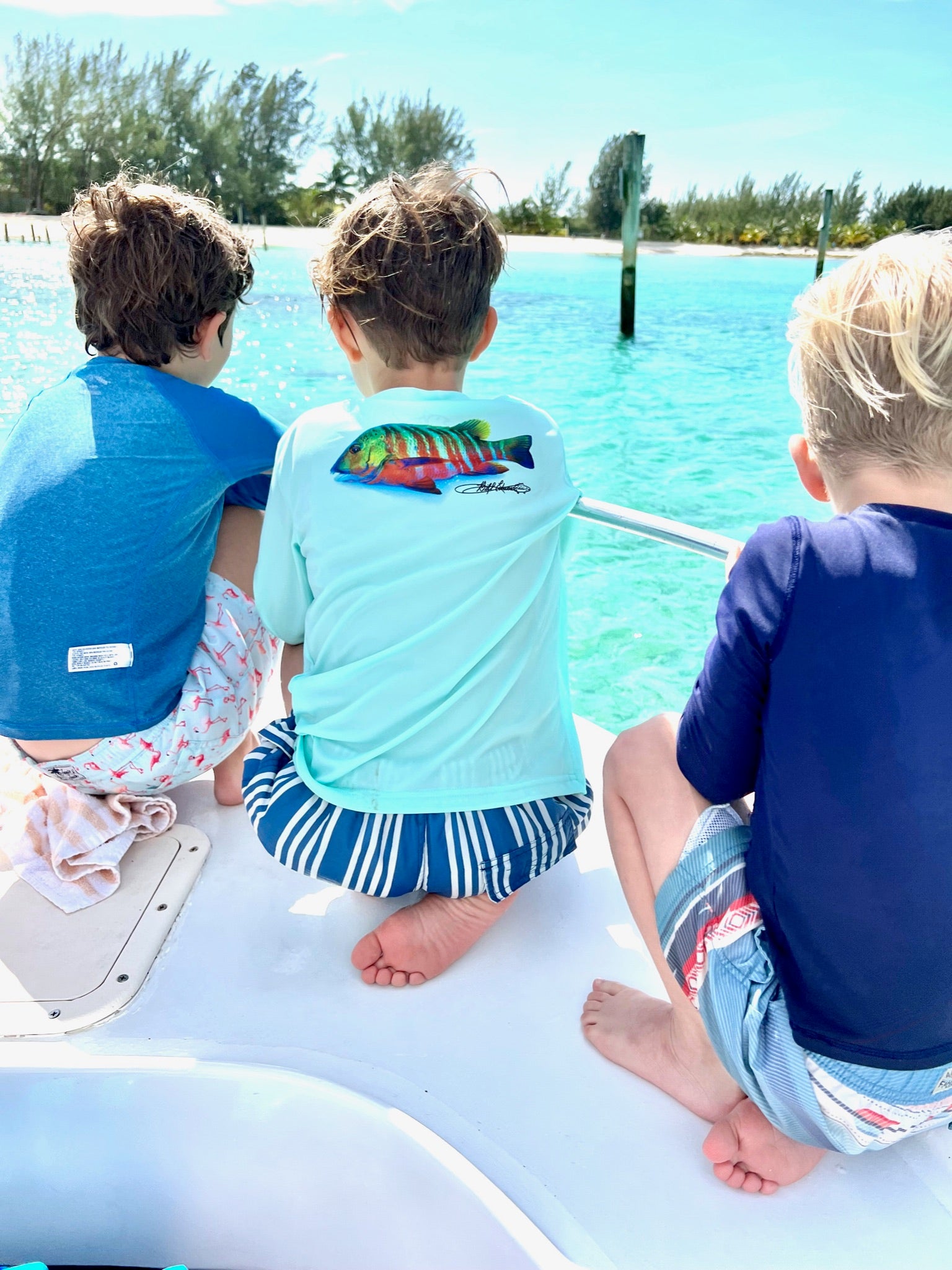 Three boys wearing Santiago Snapper Kids Performance Fishing Shirts UPF 50+ on a boat, showcasing colorful snapper design and beach-ready activewear.