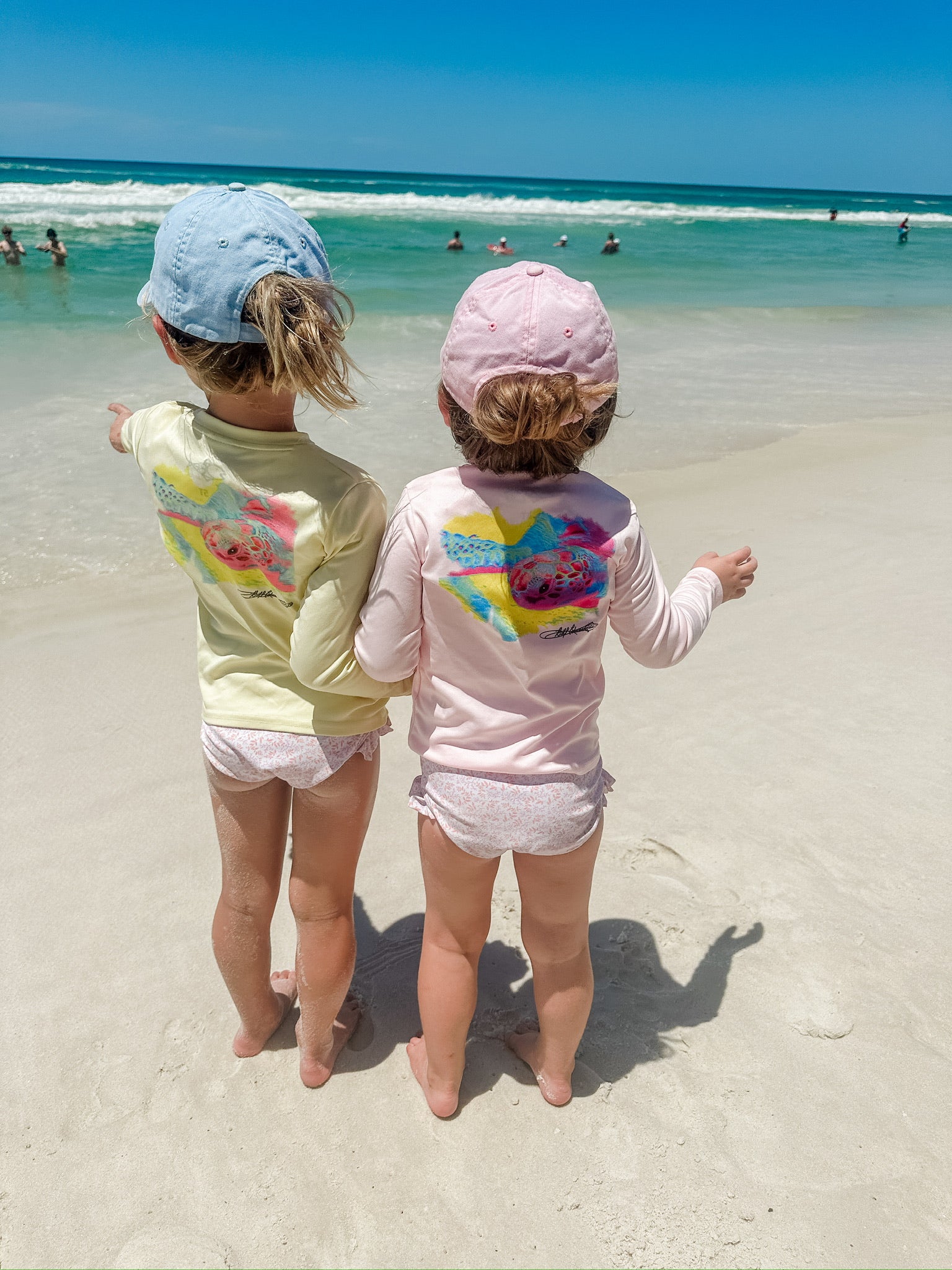 Two toddlers wearing Mr. Turtlehead Kids Performance Fishing Shirts with sea turtle design at the beach, showcasing UPF 50+ sun protection.