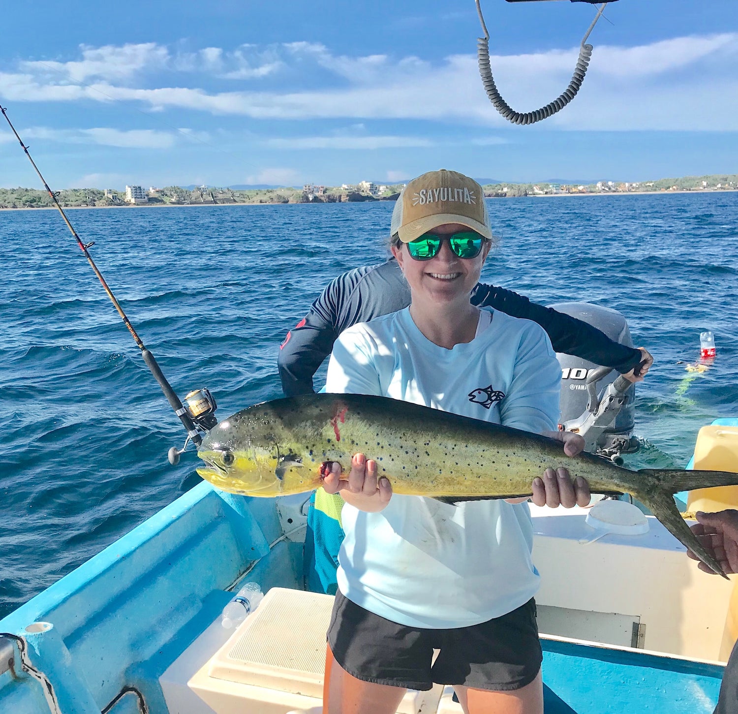 Woman holding fish on boat in Rainbow Trout UPF 50+ Shirt, showcasing breathable fabric and front logo for fishing enthusiasts.
