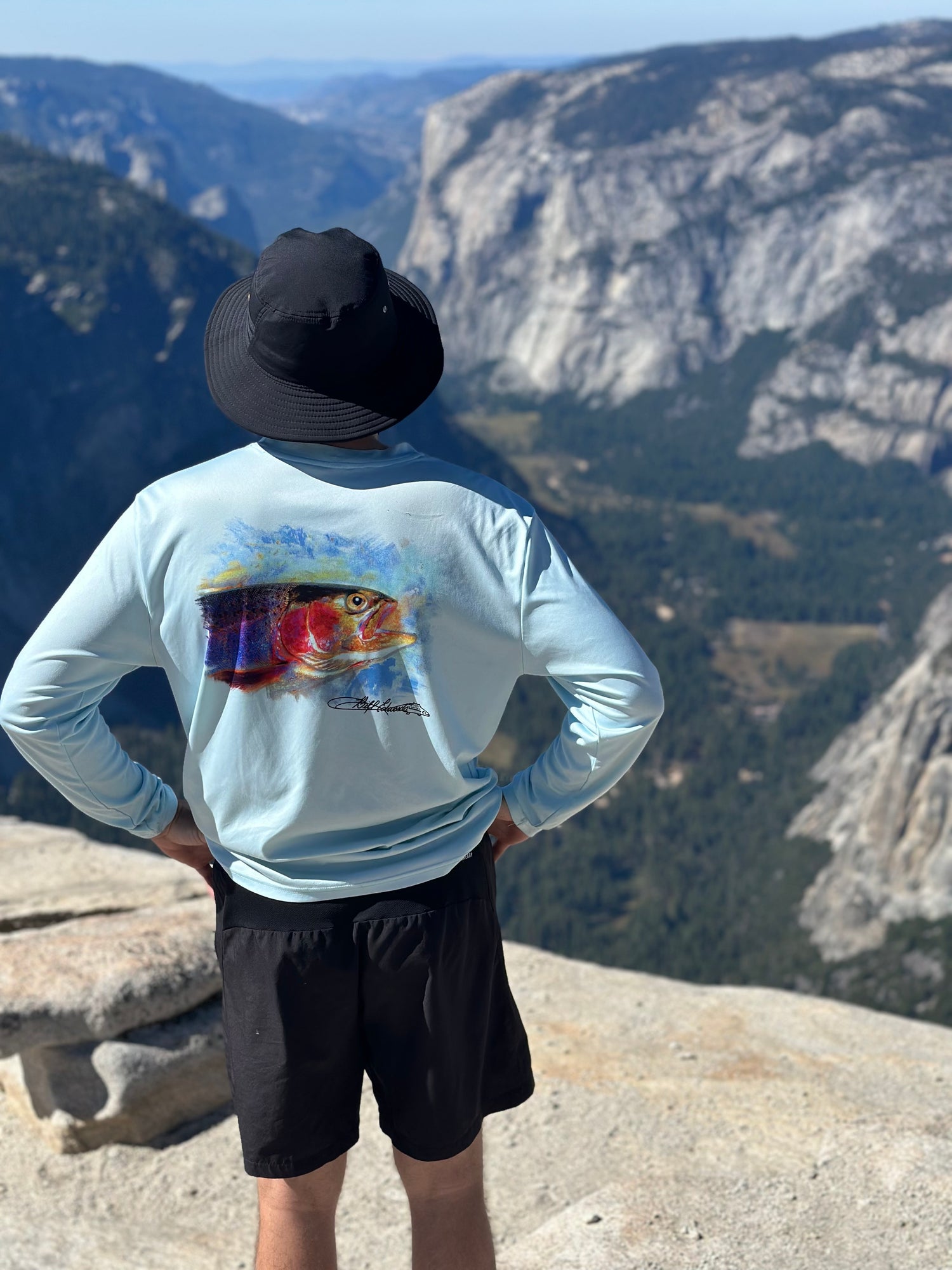 Man overlooking mountain valley in Rainbow Trout UPF 50+ Shirt, emphasizing sun protection and scenic outdoor performance wear.
