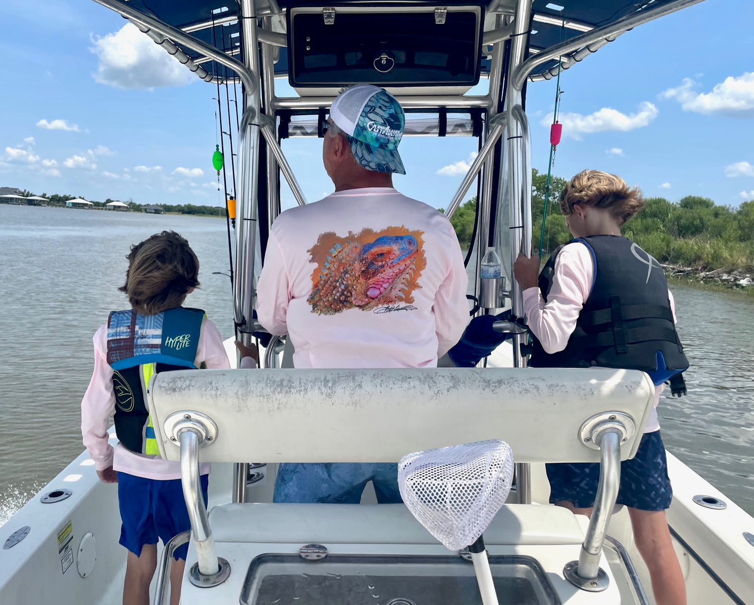 Man wearing Caribbean Iguana Performance Fishing Shirt - UPF 50+ with original iguana artwork on back, fishing on a boat with two kids.
