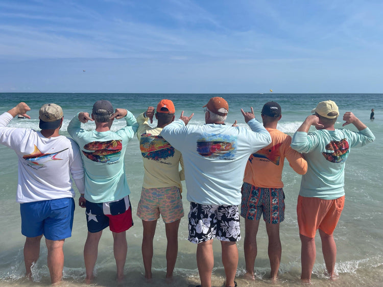 Group of men wearing colorful adult performance fishing shirts on beach.