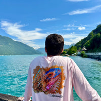 Man wearing Caribbean Iguana Performance Fishing Shirt - UPF 50+ with vibrant iguana artwork, standing by a scenic lake with mountains in the background.