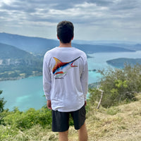 Man wearing Marlin Performance Fishing Shirt with UPF 50 sun protection, featuring colorful marlin artwork by Bill Edwards, overlooking a scenic lake view.