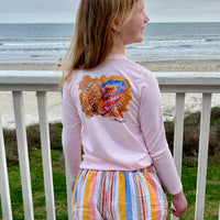 Girl wearing Caribbean Iguana Kids Performance Fishing Shirt UPF 50+ with iguana design on back, standing on beachside deck.