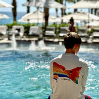 Boy wearing Redfish Design Fishing Shirt with UPF 50 by a resort pool. Long sleeve performance shirt offers sun protection and moisture wicking comfort.