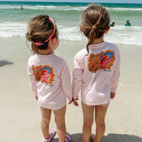 Two kids at the beach wearing matching Caribbean Iguana Kids Performance Fishing Shirts UPF 50+ with iguana back print.