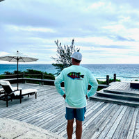 Man wearing Santiago Snapper Performance Fishing Shirt UPF 50+ Sun Protection Moisture-Wicking on oceanfront deck. Long sleeve shirt with colorful snapper graphic.