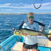Woman holding fish on boat in Rainbow Trout UPF 50+ Shirt, showcasing breathable fabric and front logo for fishing enthusiasts.