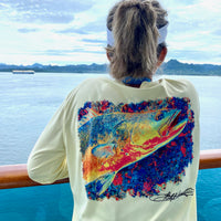 Woman wearing Speckled Trout UPF 50+ Fishing Shirt with colorful trout design while overlooking the ocean, showcasing sun-safe fishing apparel.